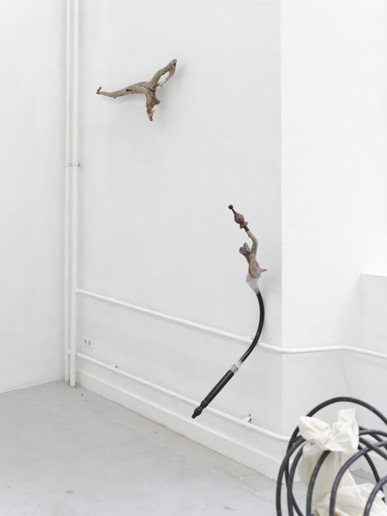 Foto: Aufnahme einer Raumecke mit weißen Wänden und hellgrauem Boden. An der Wand montiert befinden sich auf unterschiedlicher Höhe gewundene Objekte.