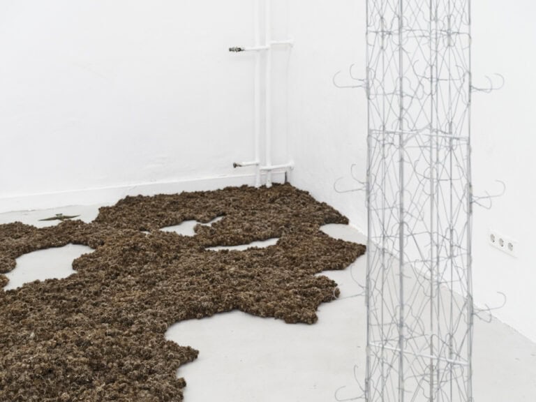 Foto: Aufnahme einer Raumecke mit weißen Wänden und hellgrauem Boden. Auf dem Boden und im Raum befinden sich Objekte.