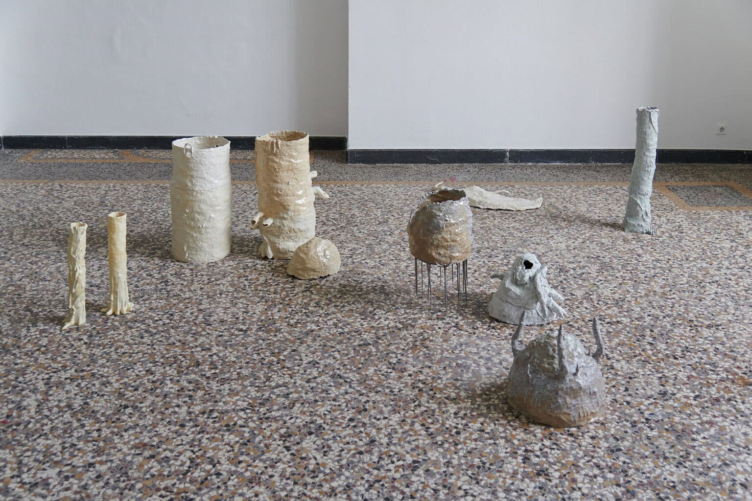 Foto: Mehrere, nah aneinander stehende Objekte auf mehrfarbigen Steinboden.