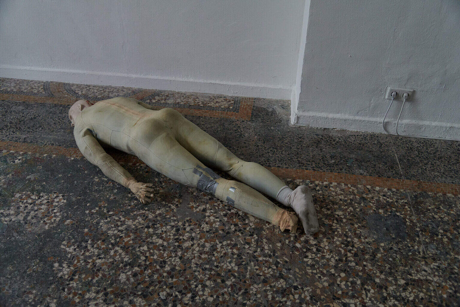 Foto: Ein beschädigter und verschmutzen Crashtest-Dummy, der auf dem Bauch auf dem Boden liegt.