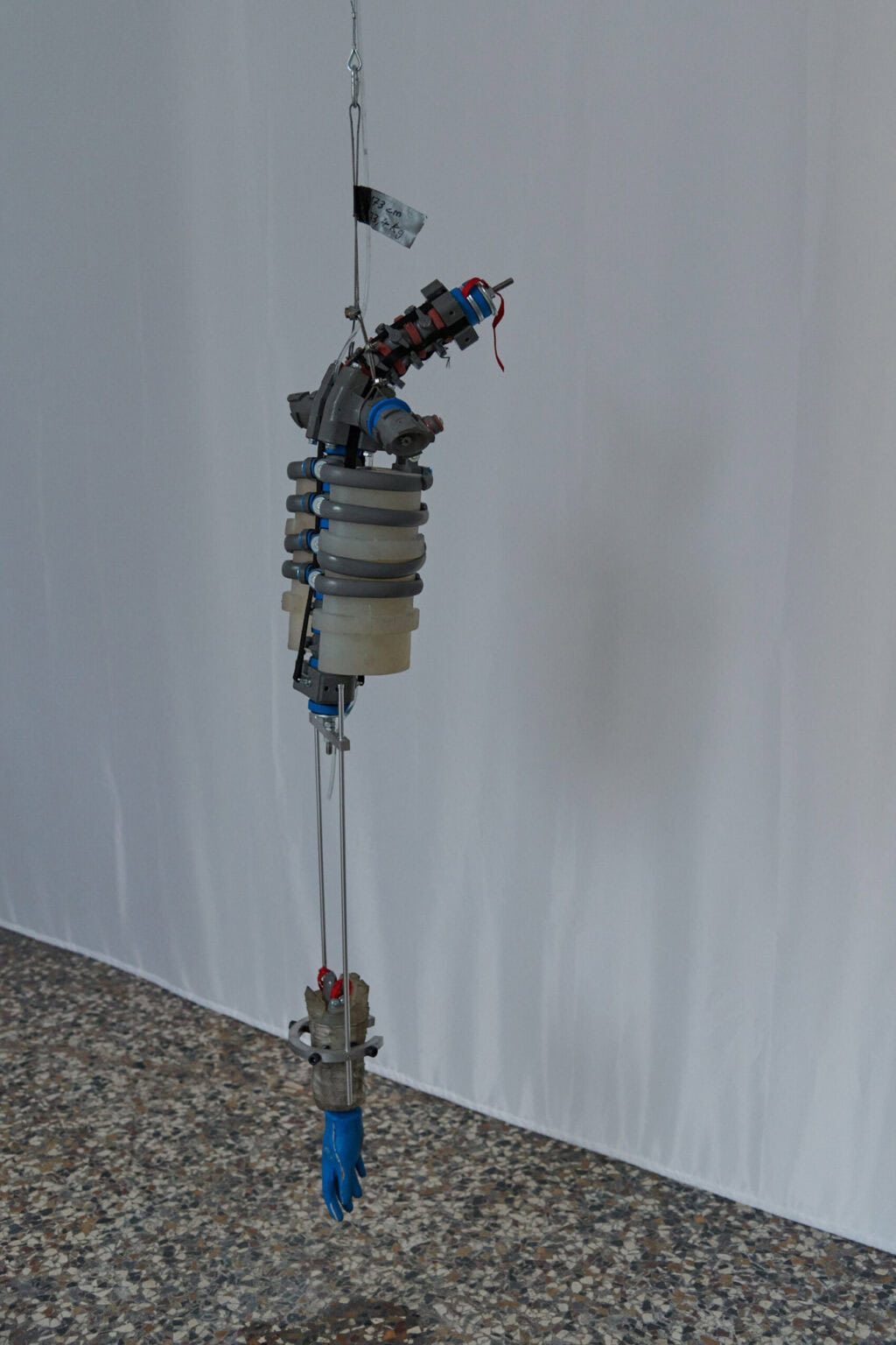 Foto: Ein längliches, von der Decke hängendes Objekt aus unterschiedlichen Materialien.