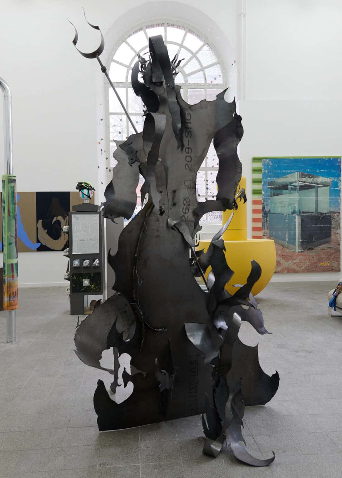 Foto: Ansicht eines Raumes mit weißen Wänden, großen Bogenfenster und grauem, gekachelten Boden. Im Raum und an den Wänden befindet sich eine Vielzahl von großen Objekten, die dich beieinander stehen.