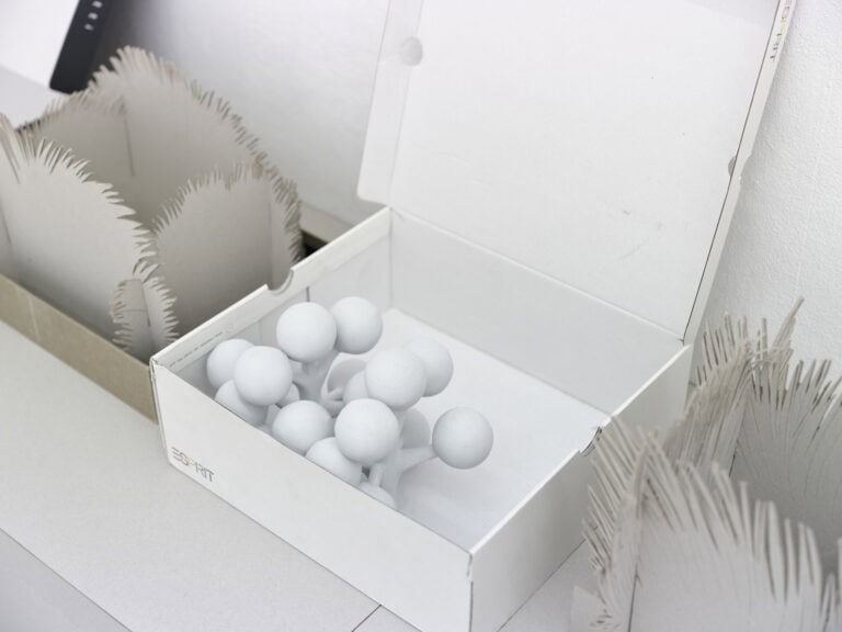 Foto: Nahaufnahme von Objekten in weißer und grauer Farbe vor einer weißen Wand.