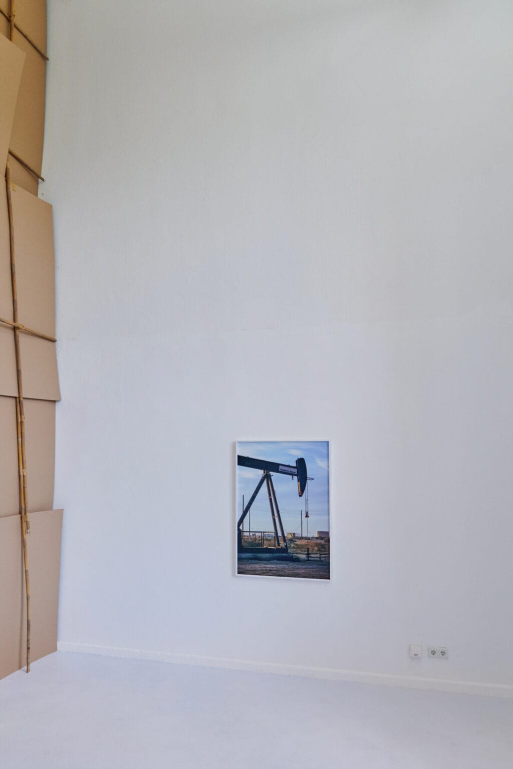 Foto: Ein Raum mit weißen Wänden und hellgrauem Boden. An der Wand ein mittelfromatiges Objekt.