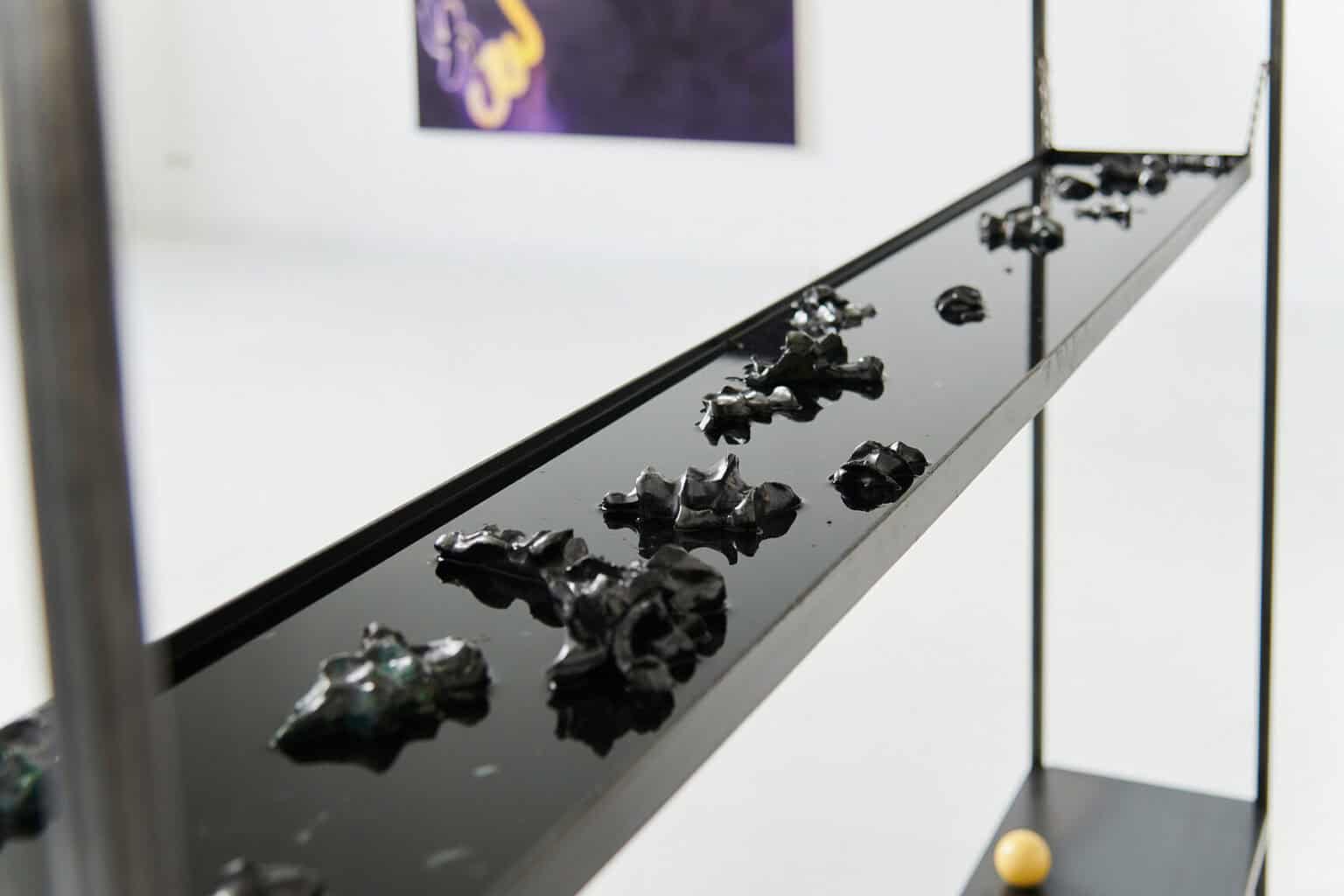 Foto: Nahaufnahme eines Regals, in dessen Regalbrett mit Vertiefung sich Objekte und Flüssigkeit befinden.