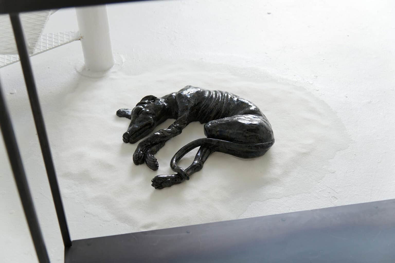 Foto: Auf dem weiß gestrichenen Boden liegt ein glänzendes Objekt auf einem Haufen weißem Sand.