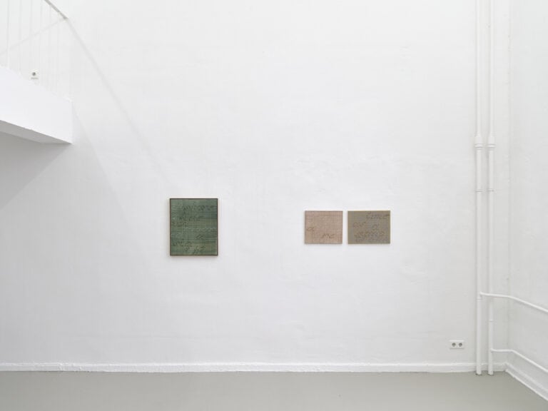 Foto: Ansicht eines Raumes mit weißen Wänden und grauem Boden. An den Wänden hängen, auf gleicher Mittellinie, drei Arbeiten auf Leinwand.