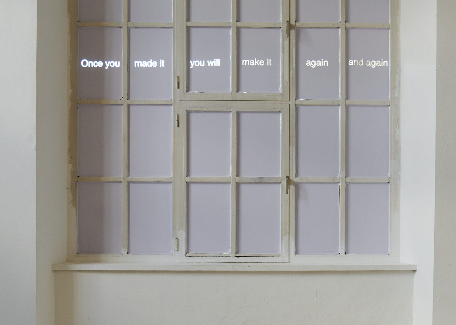 Foto: Ansicht eines großen Fenster, dessen Scheiben mit weißen Material abgedunkelt sind. Auf den abgedunkelten Scheiben die Schrift: "Once you made it you will make it again and again".