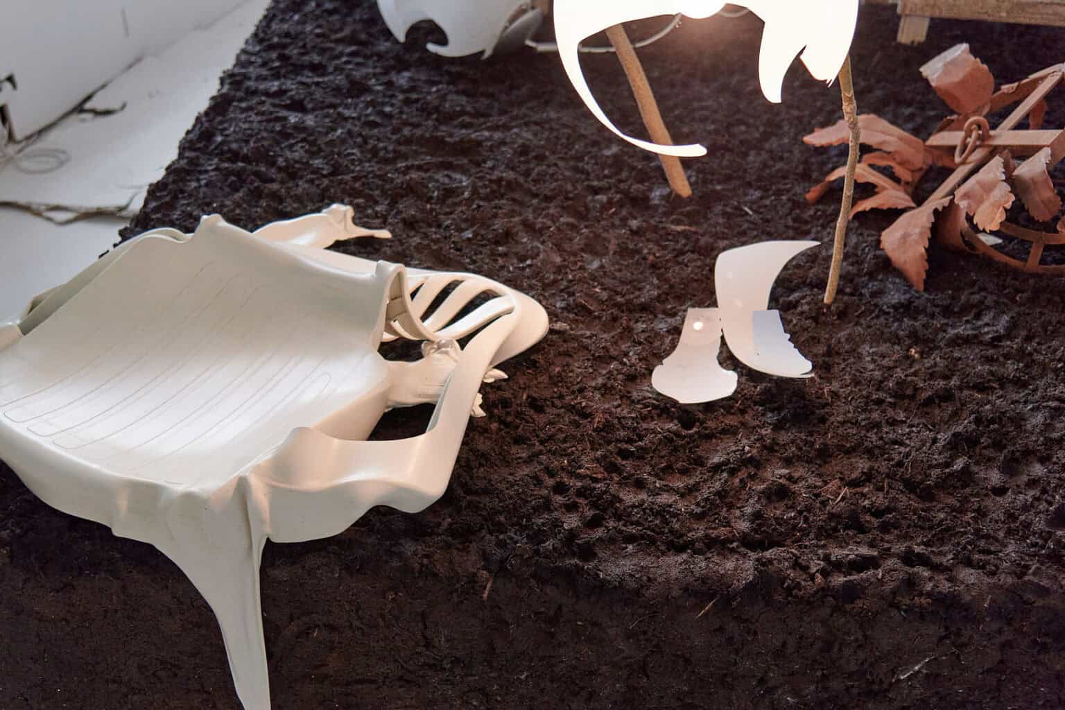 Foto: Nahaufnahme von zum Teil zerbeulten und fragmentierten Objekten und Stöcken in und auf Erde.