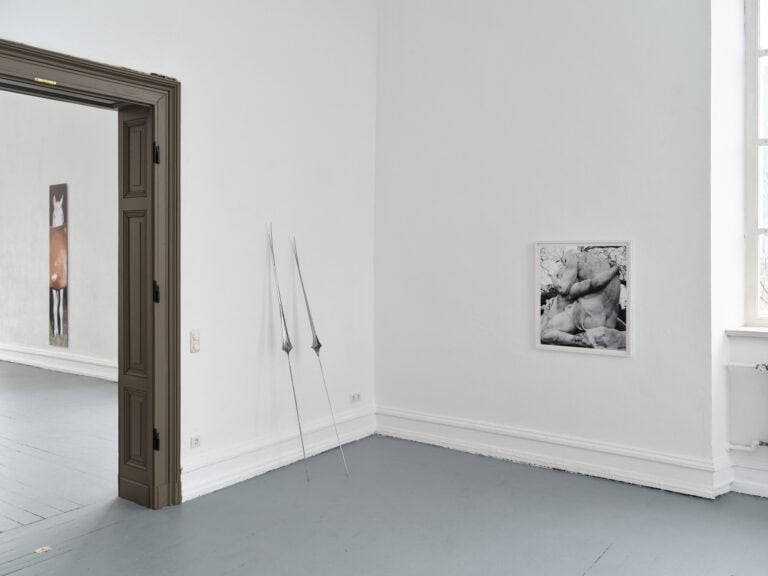 Foto: Ansicht eines Raumes mit weißen Wänden und grauem Boden. An den Wänden hängend oder lehnen Objekte.