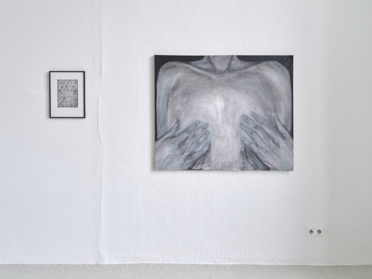 Foto: Ansicht einer weißen Wand, unten im Bild grauer Boden. An der Wand befinden sich zwei flache Objekte in Klein- und Mittelformat.