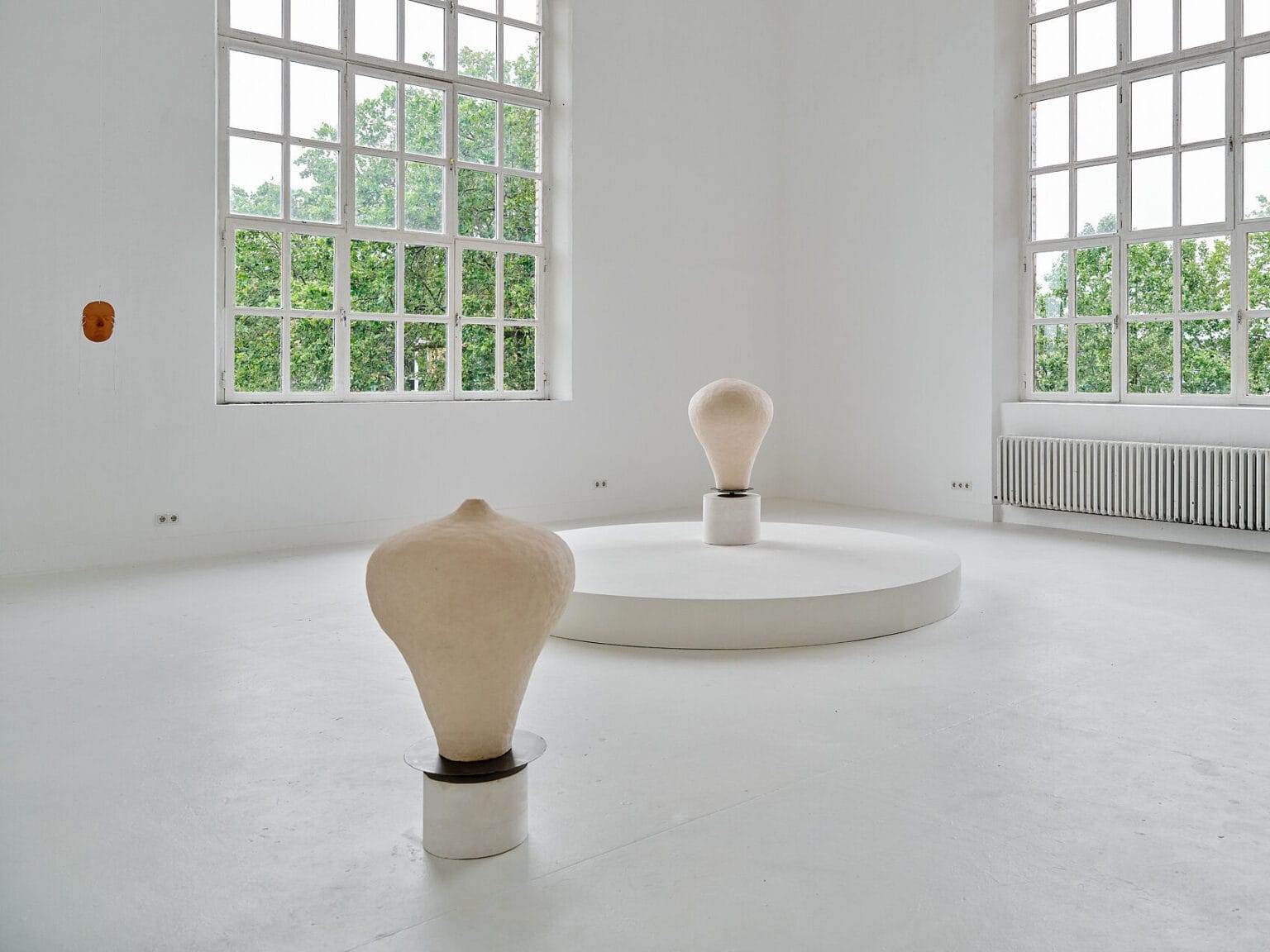 Foto: Ansicht eines Raumes mit weißen Wänden, weißem Boden und zwei großen Fenstern. Im Raum und an den Wänden befinden sich Objekte.