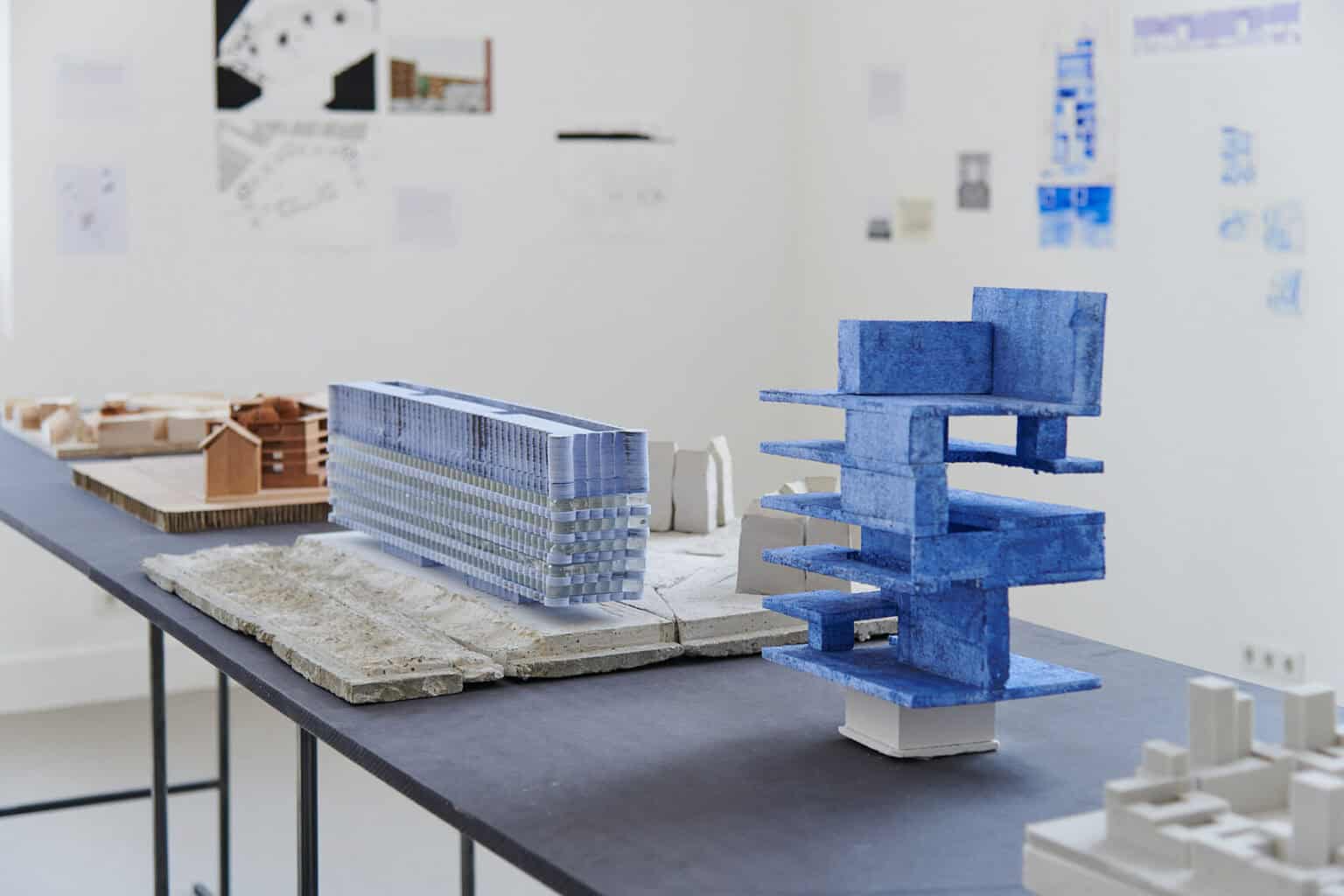 Foto: Architektonische Modelle aus unterschiedlichen Materialien auf einem schwarzen Tisch.