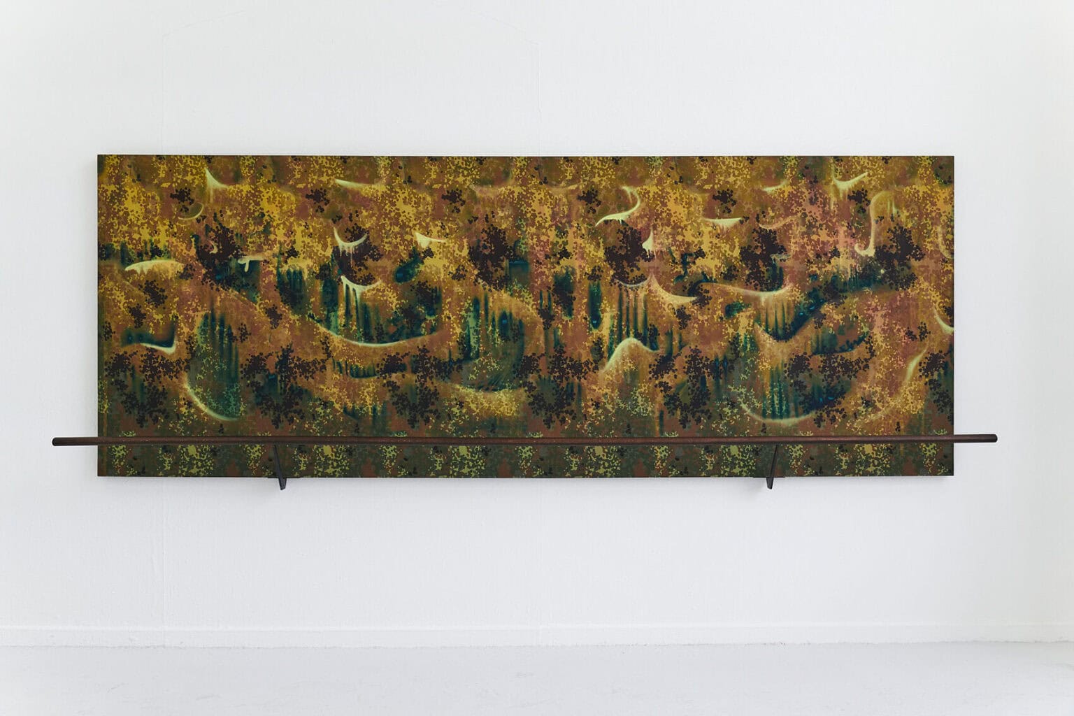 Foto: Ansicht eines großformatigen, flachen Objektes aus unterschiedlichen Materialien vor weißer Wand.