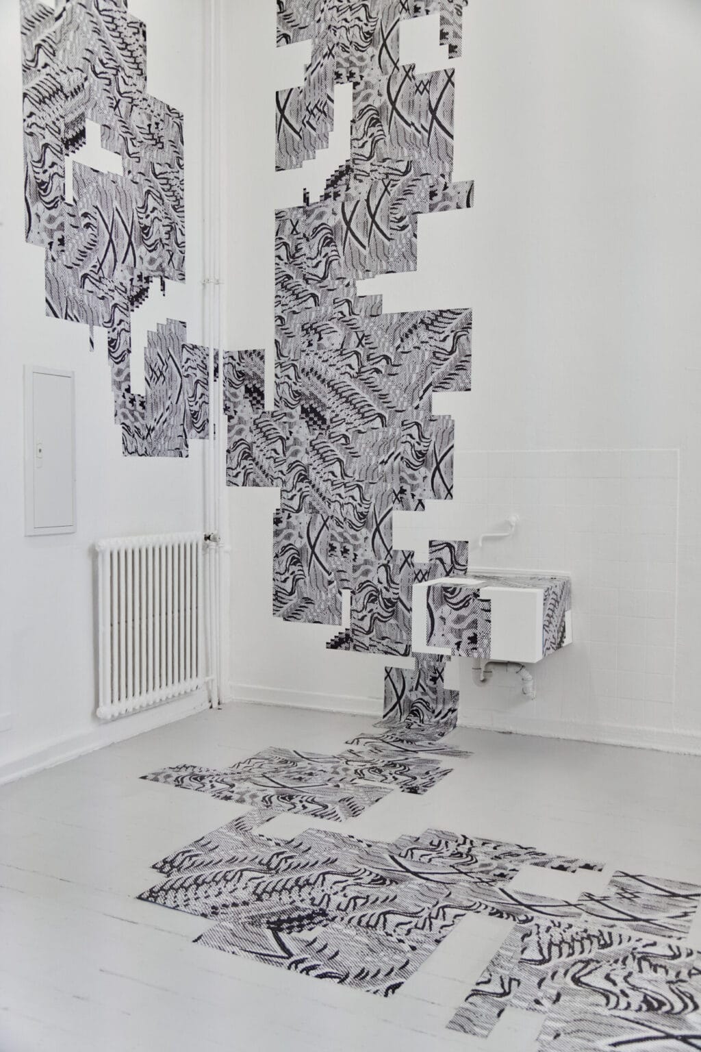 Foto: Eine Gruppe von flachen, gemusterten Objekten, die sich von Oben- bis unten über die Wand und über den Boden erstreckt.