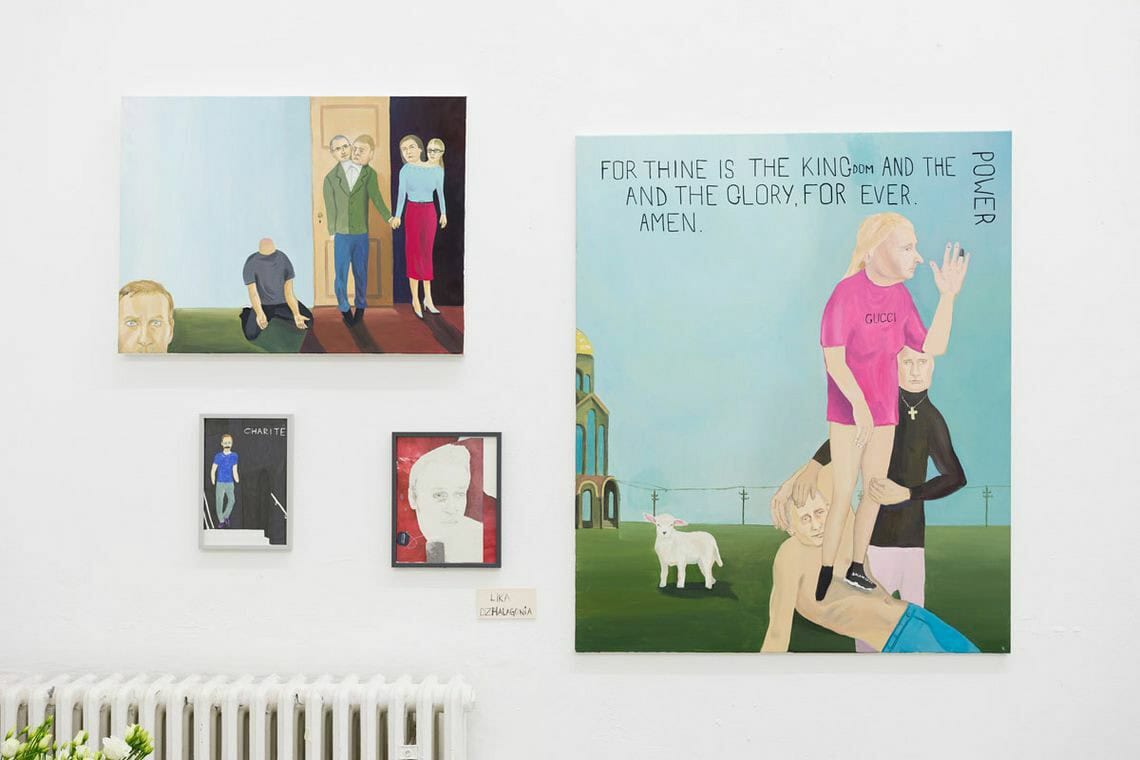 Foto: Eine weiße Wand, auf der gerahmte und ungerahmte Objekte in Mittel- und Kleinformaten hängen.