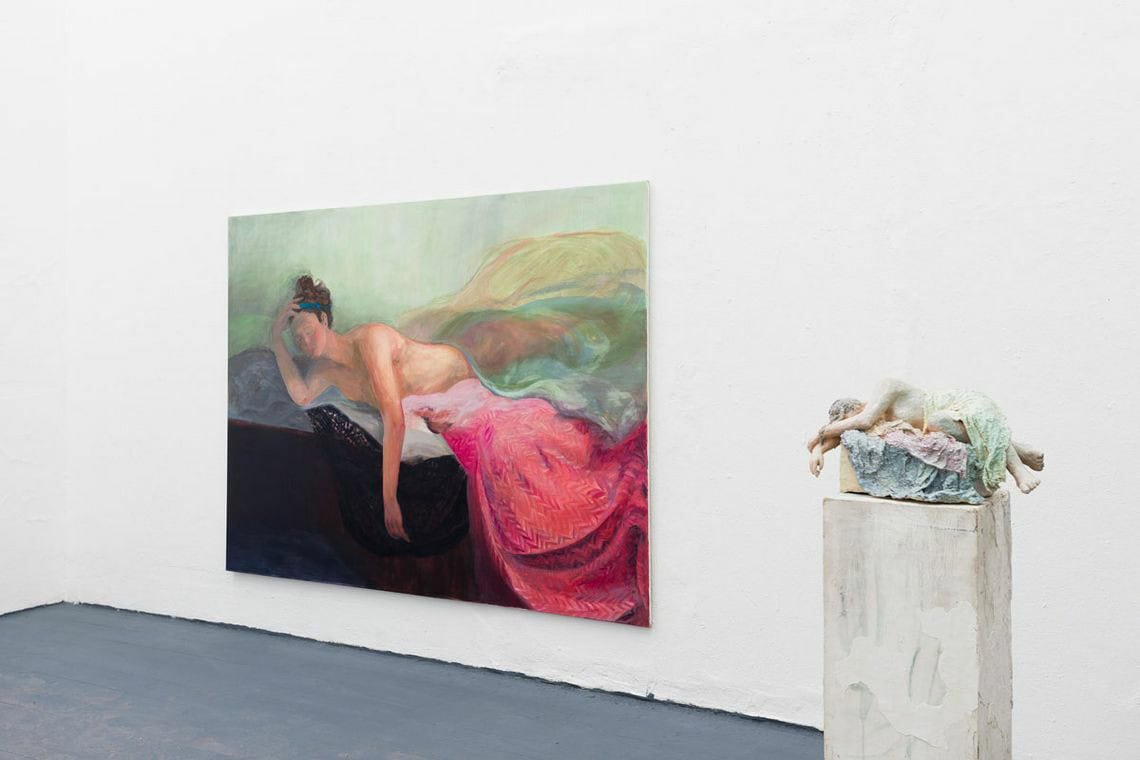 Foto: Ein Raum mit weißen Wänden und grauem Boden. An der Wand eine großformatige Leinwandarbeit. Im Raum eine Skulptur.