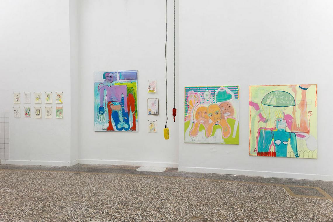 Foto: Ein Raum mit weißen Wänden, mehrfarbigem Steinboden und einer Bogenförmigen Einbuchtung in der Wand. An der Wand hängen mehrere Papiere und Leinwände.