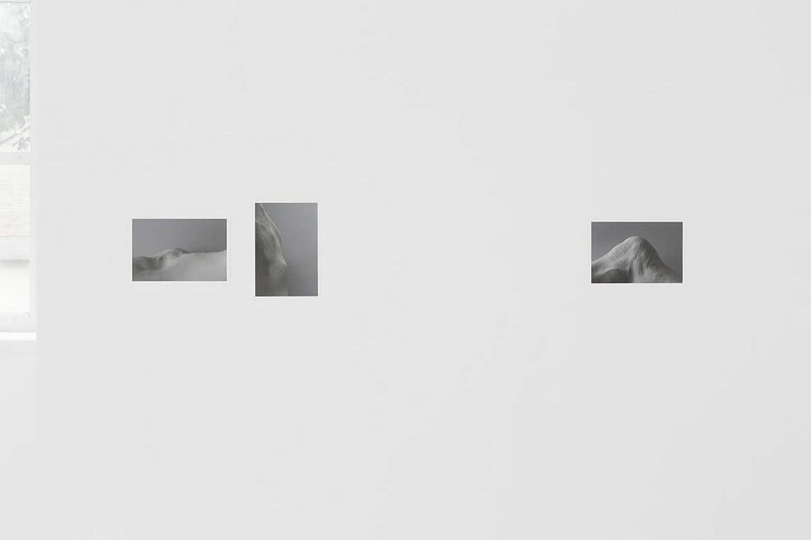 Foto: Eine weiße Wand auf der drei kleine, flache Objekte angebracht sind.