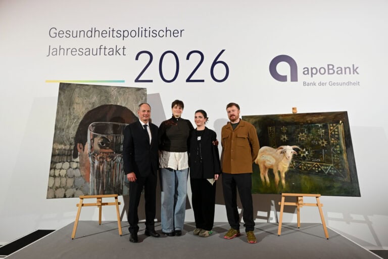 Foto: 4 Personen auf einer Bühne vor 2 Gemälden stehend. Auf der Wand dahinter steht "Gesundheitspolitischer Jahresauftakt 2026" und "apoBank, Bank der Gesundheit"